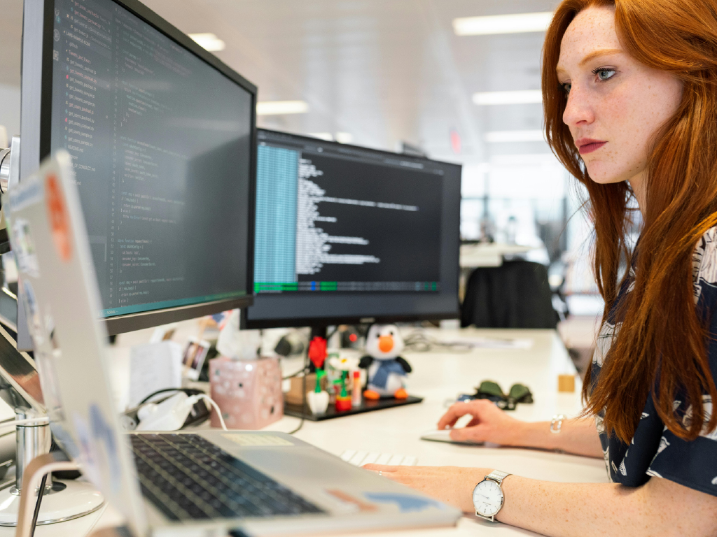 Profissional de tecnologia analisa códigos no computador em ambiente de escritório moderno, promovendo inovação e soluções digitais.