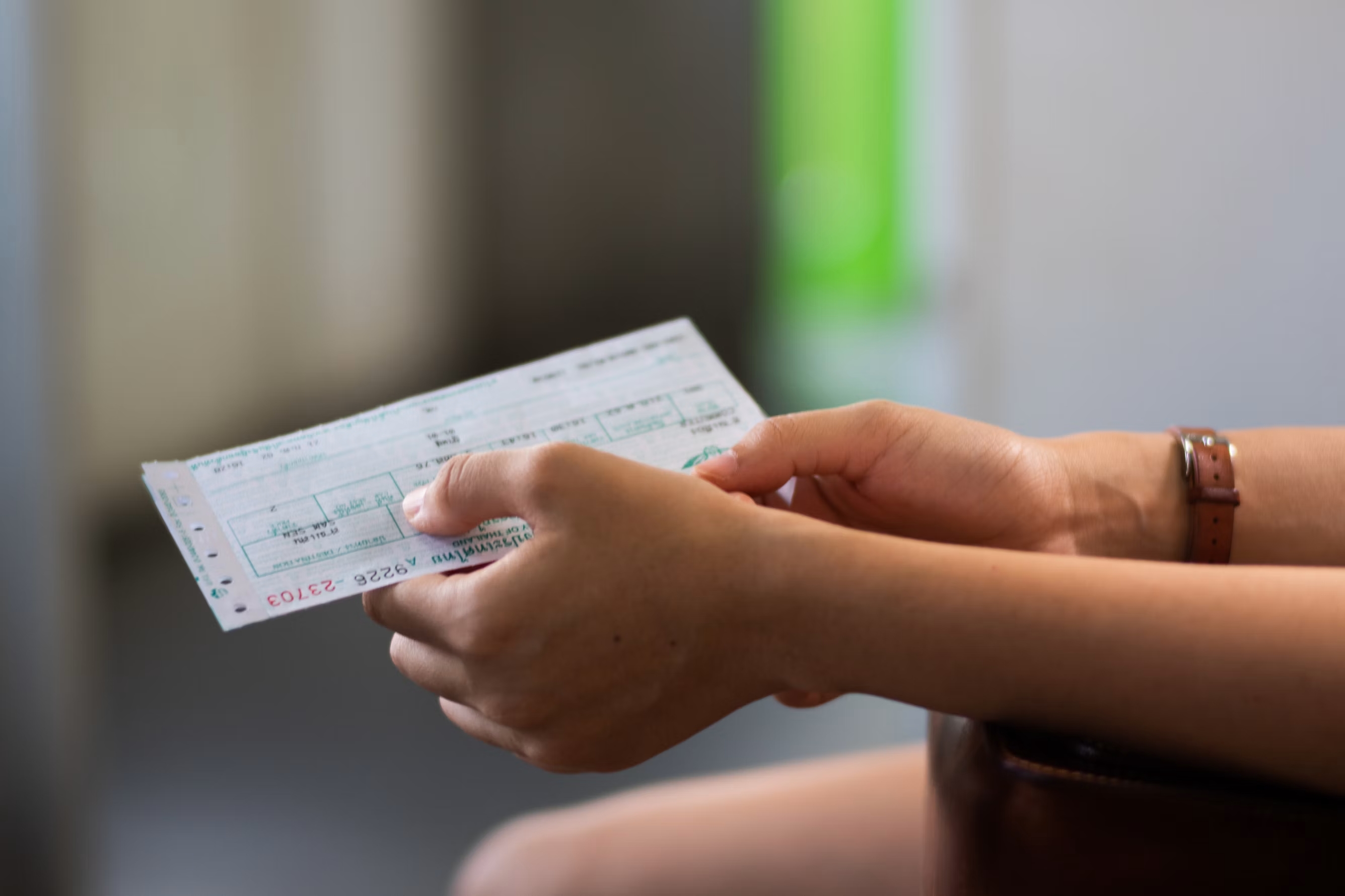 Pessoa segurando um ingresso na mão, com um fundo desfocado de um evento ou local de entretenimento.