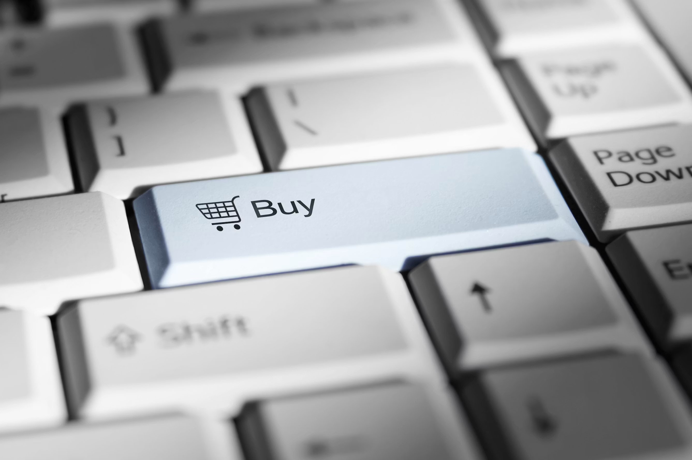 Teclado de computador em destaque na tecla “Buy” com ícone de carrinho de compras, em foco na interface de e-commerce e compras online.
